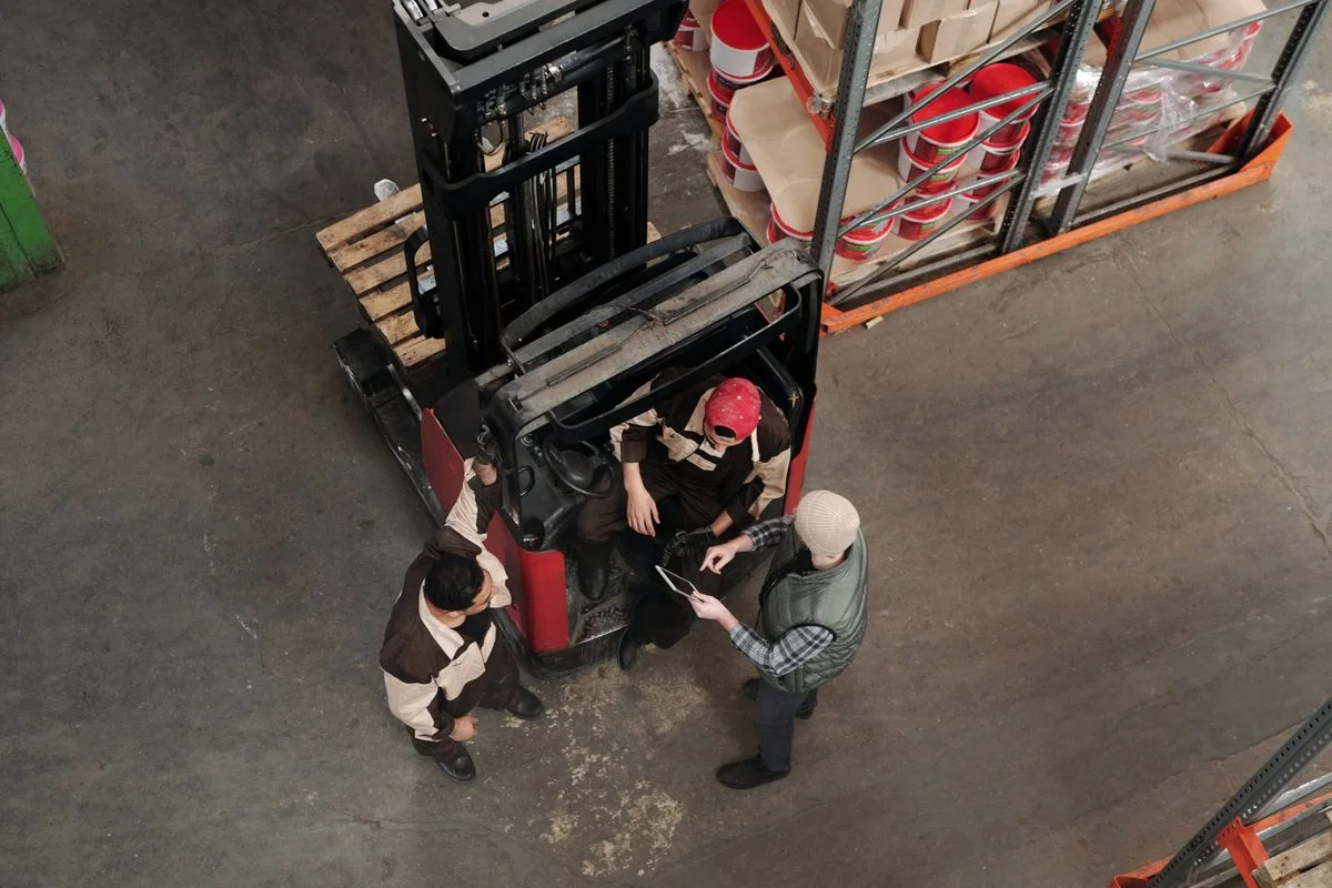 Warehouse employees discussing logistics near industrial handling equipment